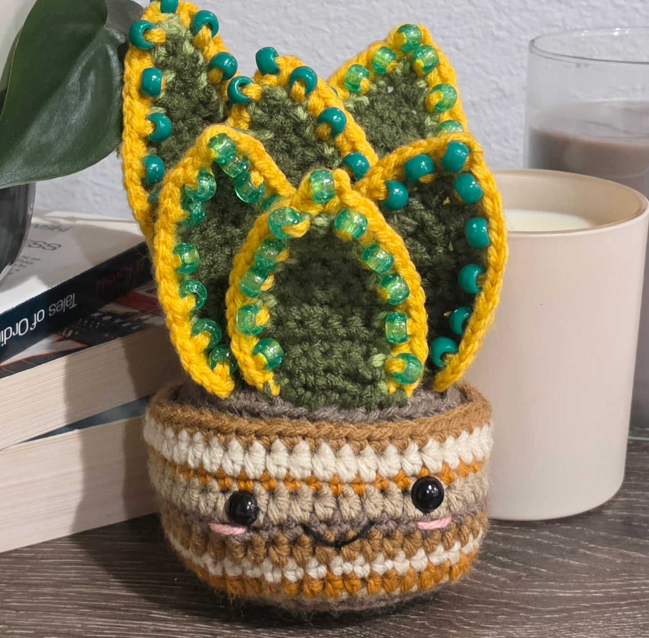Crocheted snake tongue plant with a face on a wooden surface
